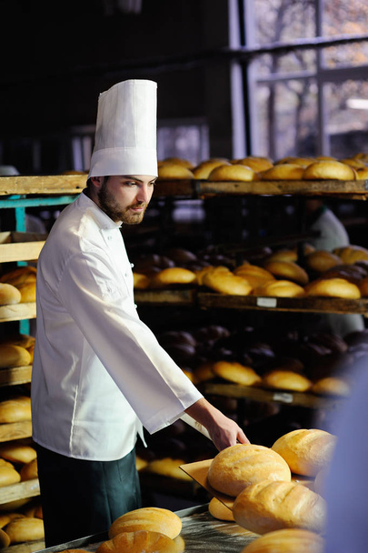 baker pulls out of the oven fresh bread - Fotó, kép