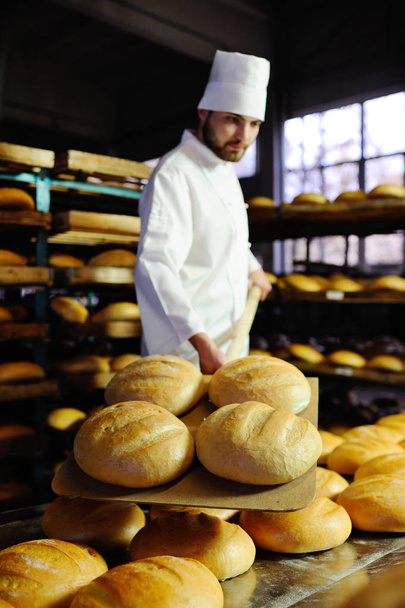 baker pulls out of the oven fresh bread - Fotó, kép
