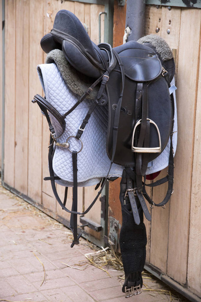 Skórzane siodło do sportów jeździeckich, wiszące w stodole  - Zdjęcie, obraz