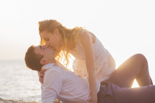 Young couple kissing on seaside at golden sunrise - Fotoğraf, Görsel