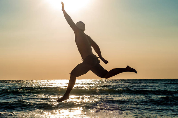 A man jumps joyfully against the sea - Foto, Bild