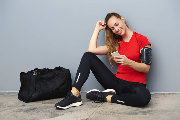 Smiling athletic woman with cell phone - Фото, изображение