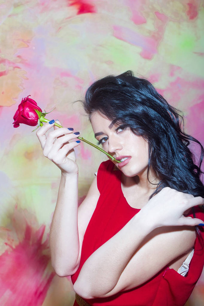 pretty girl with brunette hair holds red rose in dress - Fotó, kép