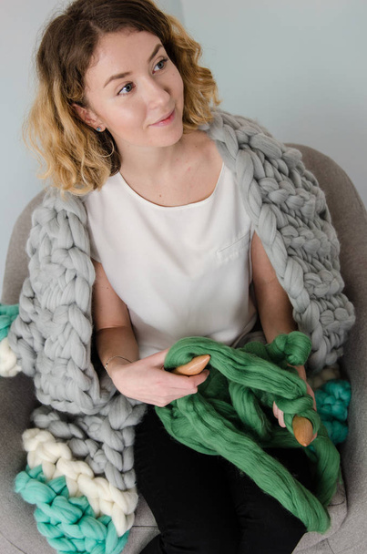young woman sitting on chair and holding merino wool in hands - Photo, Image