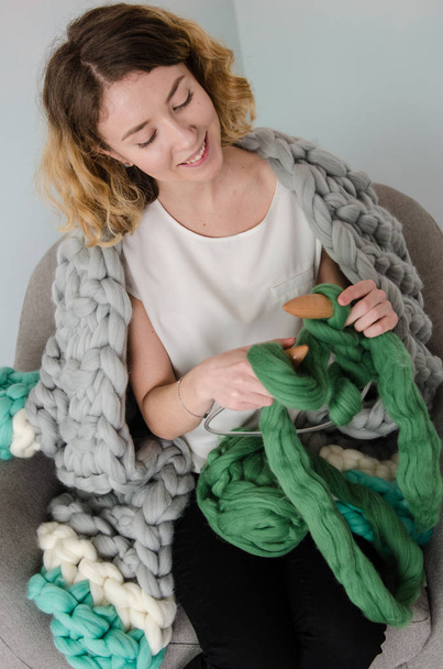 Young woman sitting and kniting with merino wool - Foto, Imagen