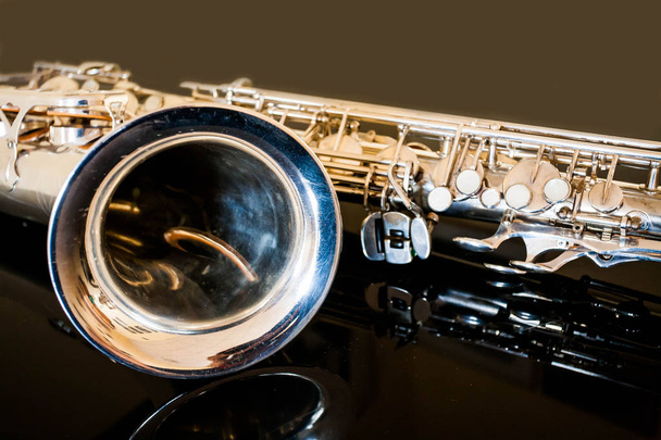 Saxophone tenor. Woodwind Classical Instrument. Jazz, blues, classics. Music. Saxophone on a black background. Black mirror surface. Music styles - Photo, Image