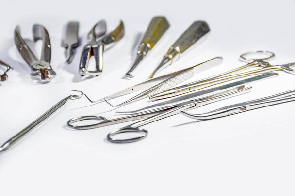 Dental Instruments some arranged and some not arranged on white table arranged in some pattern. - Photo, image