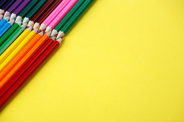 Colored pencils angle. Many different colored pencils on yellow background - Foto, imagen