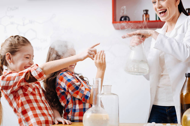 Girls trying touch chemical flask  - Foto, Imagen
