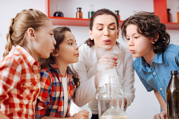 Children blowing on chemical flask - 写真・画像