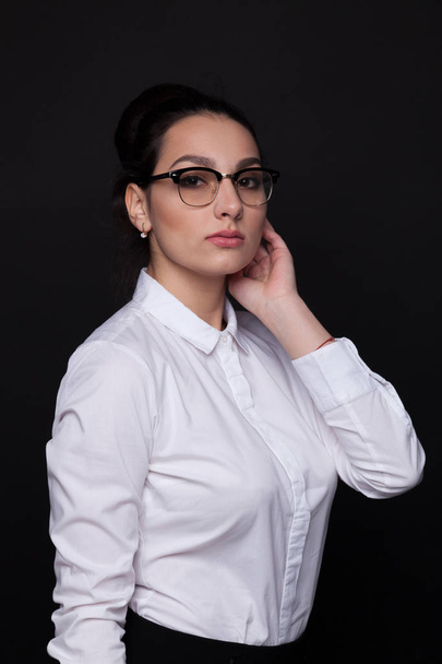 Brunette woman in black glasses on a black background - Photo, image