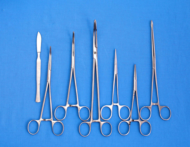 Strumenti e strumenti chirurgici, compresi bisturi, pinzette e pinzette disposti su un tavolo per un intervento chirurgico - Foto, immagini