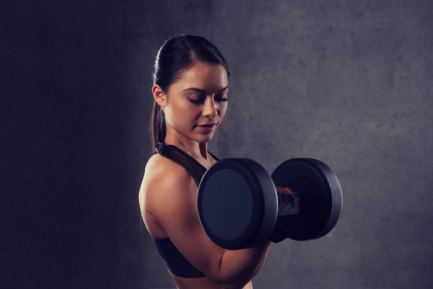 young woman flexing muscles with dumbbells in gym - Fotoğraf, Görsel