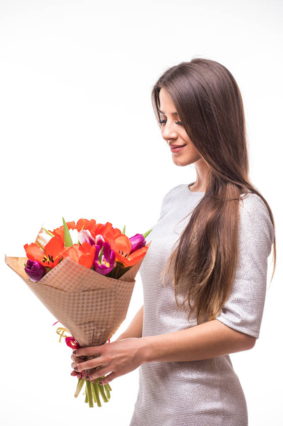 schönes Mädchen im grauen Kleid mit Blumen Tulpen in den Händen auf weißem Hintergrund - Foto, Bild