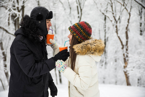 Pareja feliz bebiendo té negro juntos al aire libre en el bosque o parque de invierno
 - Foto, imagen