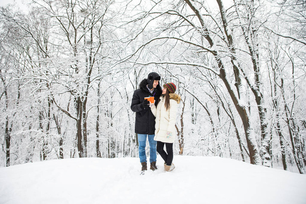 Happy couple drinking black tea together outdoors in winter forest or park - Foto, immagini