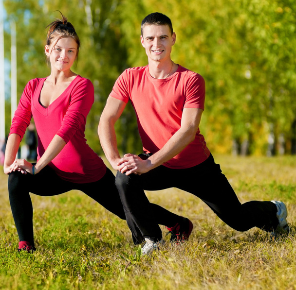 Man and woman woman doing yoga in park - Фото, зображення