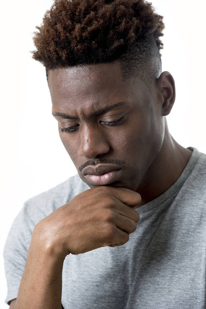 молодой привлекательный афро-американец 20-ти лет выглядит грустным и подавленным, позируя эмоциональным
 - Фото, изображение