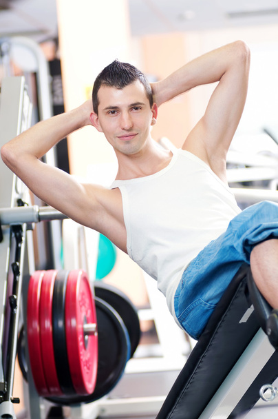 Young man doing exercises at gym - Фото, изображение