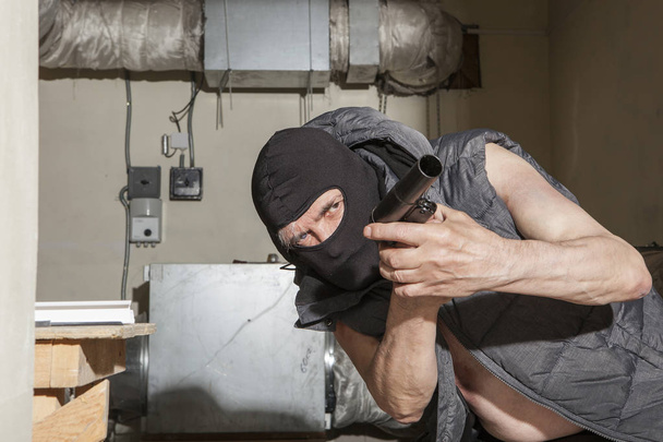 Bewaffneter Räuber mit Waffe auf dem Dachboden - Foto, Bild