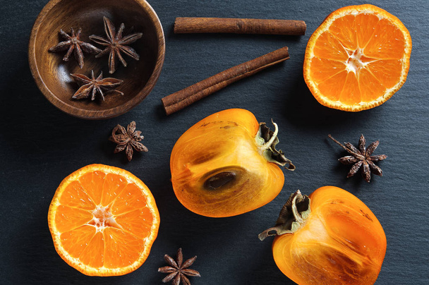Top flat view: persimmon and tangerine, anise star, cinnamon sticks - Photo, Image