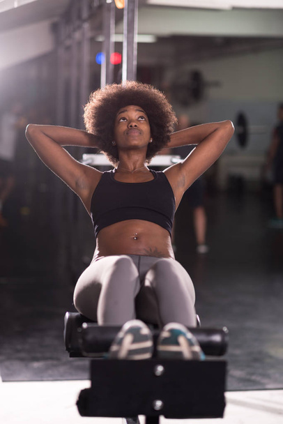 black woman doing sit ups at the gym - Фото, изображение