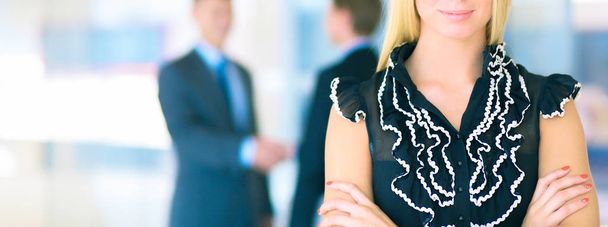 Business woman standing in foreground  in office - 写真・画像
