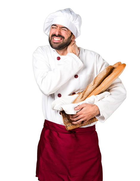 Młody piekarz trzyma chleb z bólem karku - Zdjęcie, obraz
