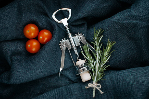 Kitchen accessory. Metal bottle opener with cork, rosemary and cherry tomatoes. - Фото, изображение