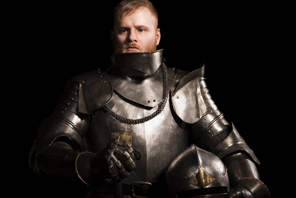Knight in armour after battle on the black background - Foto, Imagen