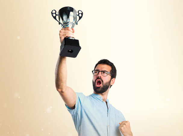 Bonito homem com óculos azuis segurando um troféu em outro backgro
 - Foto, Imagem