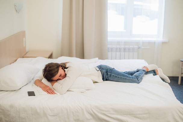 Розслаблена молода красива жінка спить у ліжку з порожнім екраном мобільного телефону
 - Фото, зображення