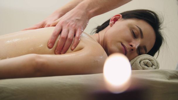 Massage à l'huile - mains mans sur le dos de la fille aux cheveux noirs
 - Photo, image