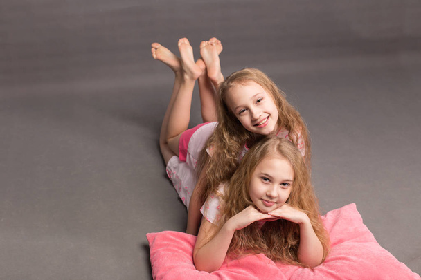 Két gyönyörű lány rózsaszín pizsama játszani lefekvés előtt - Fotó, kép