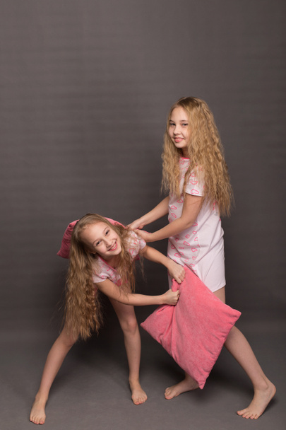 Piękny, dwie dziewczyny w różowej pidżamie grać przed pójściem do łóżka - Zdjęcie, obraz
