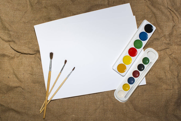 Set of watercolor paints, brushes for painting and blank white paper sheet of sketchbook. - Photo, Image
