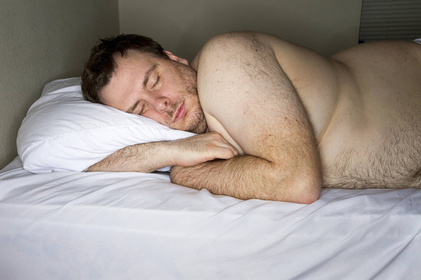 Dikke man is moe en viel in slaap in zijn bed - Foto, afbeelding