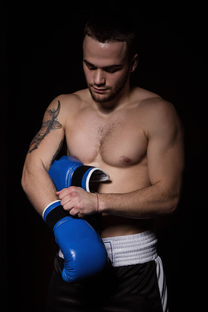 Boxer man putting on blue boxing gloves - Фото, изображение