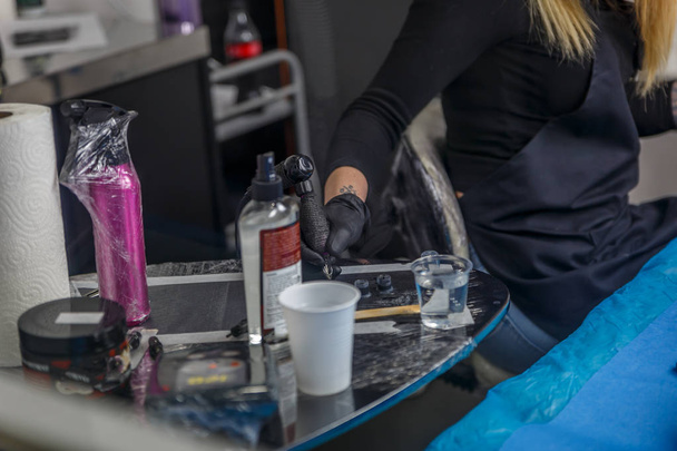 A tattoo artist is picking up ink for a tattoo in her studio - Photo, Image