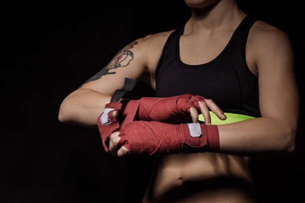 Крупный план женщины, заворачивающей руки в красные боксерские обертки
 - Фото, изображение