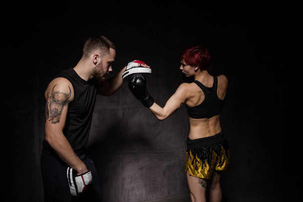 Nainen nyrkkeilijä lyömällä harjoitushanskat hallussa nyrkkeily kouluttaja
 - Valokuva, kuva