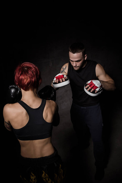 Woman boxer hitting training mitts held a boxing trainer - Foto, afbeelding