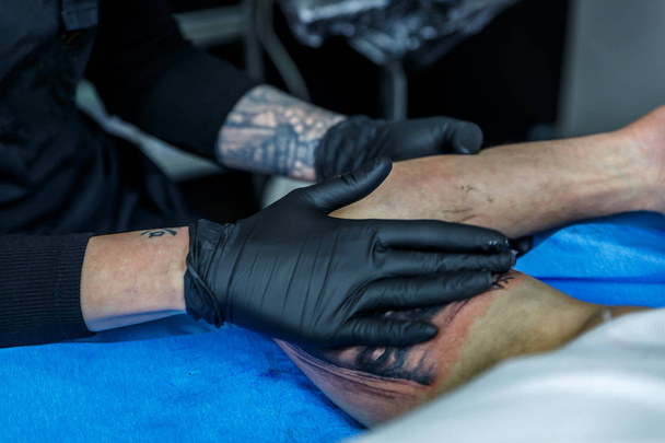 Uma artista coloca creme no braço que tatuou
 - Foto, Imagem