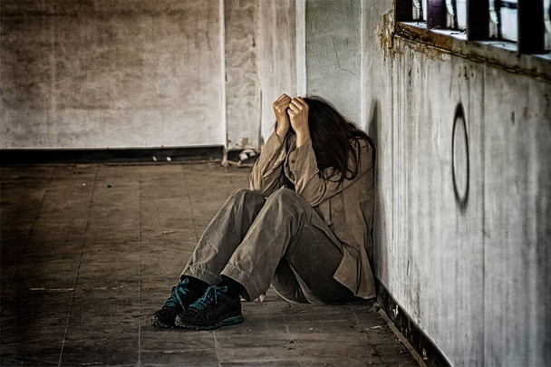 verängstigte misshandelte Frau sitzt in der Ecke auf dem Boden - Foto, Bild