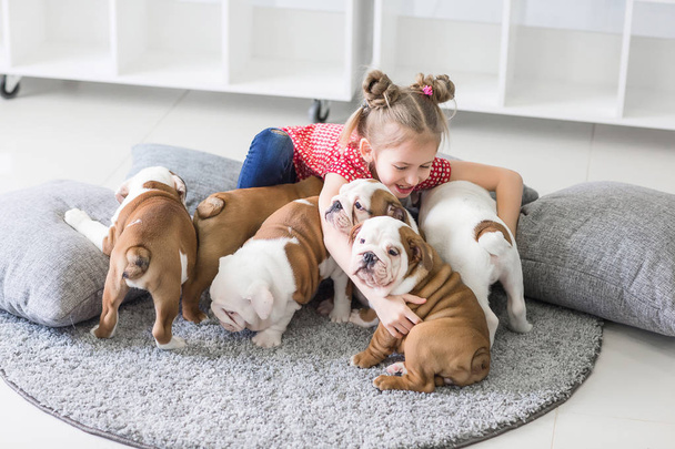 Little girl sitting on the floor and takes care of the puppies bulldog - Fotoğraf, Görsel