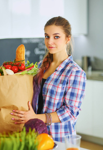 Young woman holding grocery shopping bag with vegetables - Fotó, kép