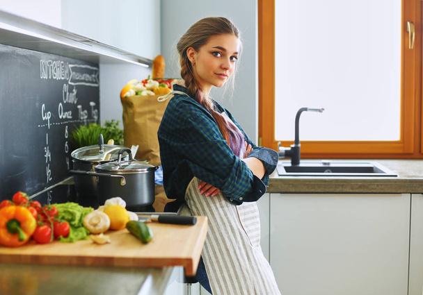 Young woman standing by the stove in the kitchen - Foto, Imagem