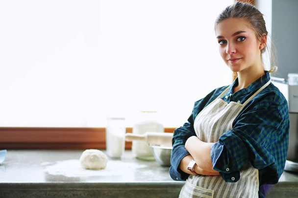 Beautiful woman cooking cake in kitchen standing near desk - Photo, Image
