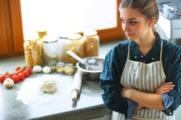 Beautiful woman cooking cake in kitchen standing near desk - Фото, изображение
