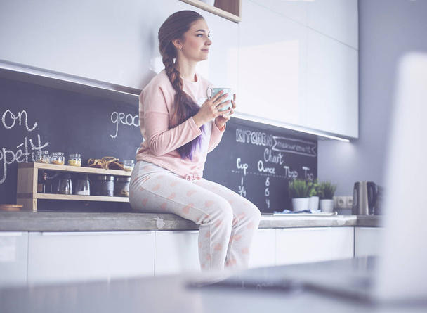 щаслива жінка п'є чай на кухні вдома
 - Фото, зображення